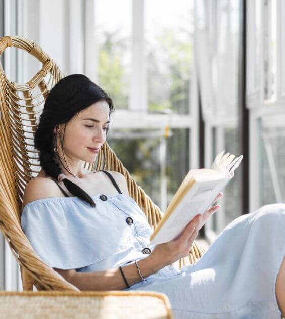 Woman Sitting in Chair Reading Book